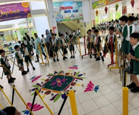 Students viewing a colourful kolam display during a school cultural event.